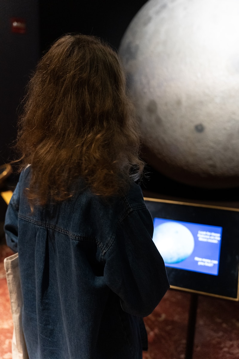 a woman standing in front of a display of planets